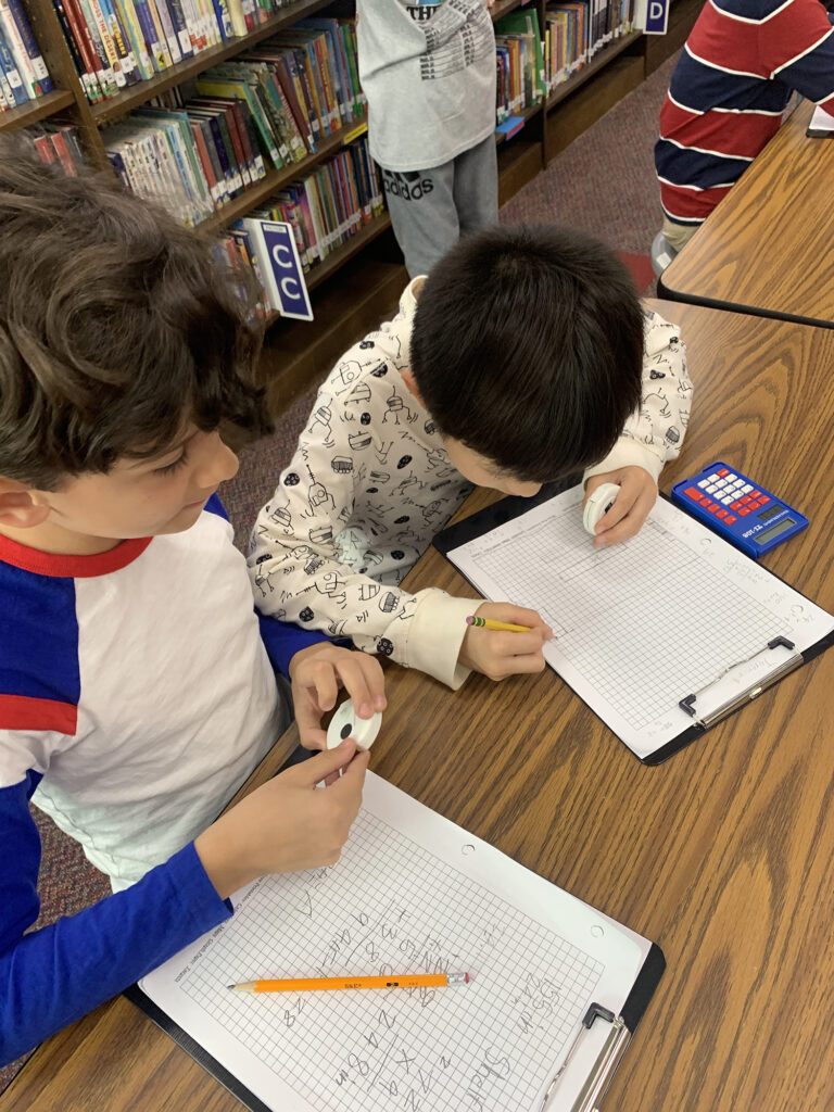 two students writing on graph paper