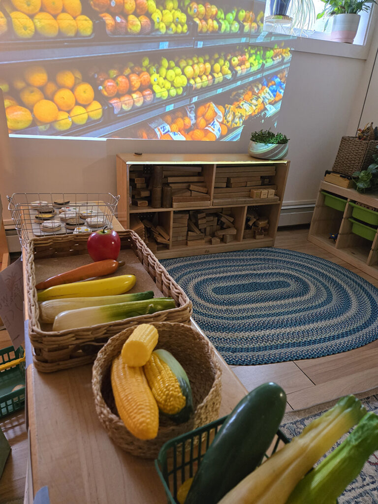 toy food on a shelf in front of a projected image of a supermarket produce departiment