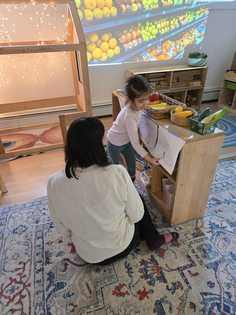 elementary student setting up play grocery store with teacher