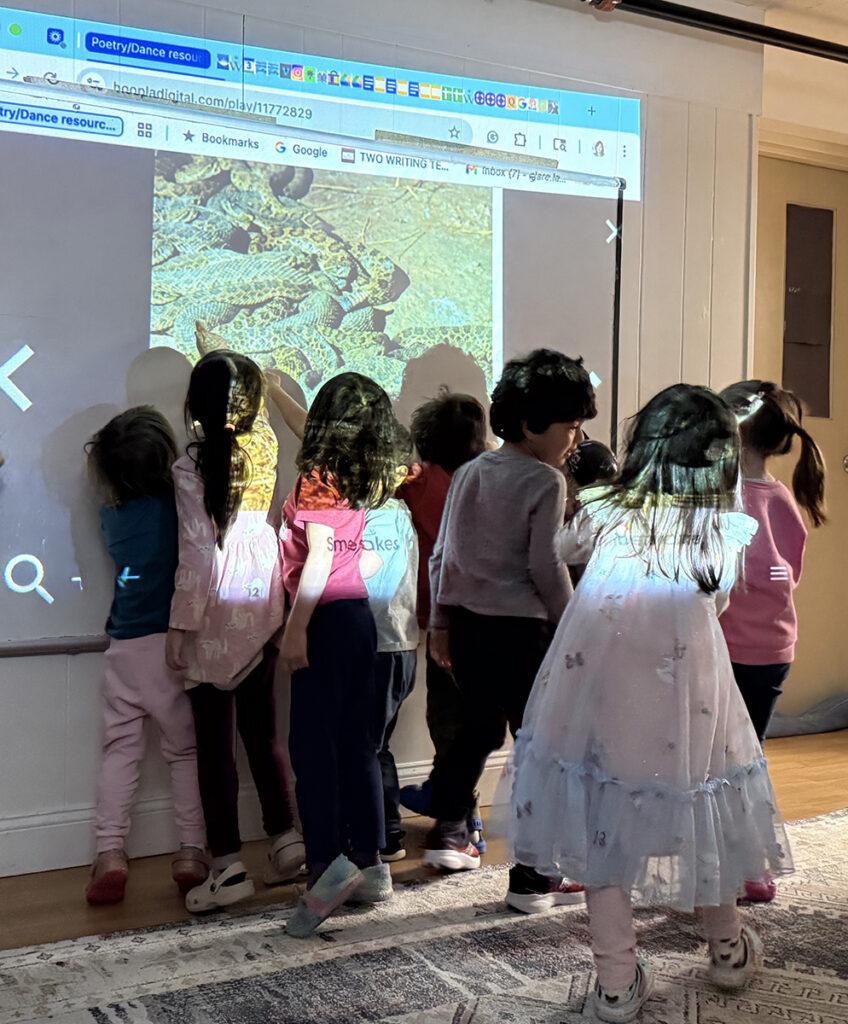 elementary students interacting with projection screen in their classroom