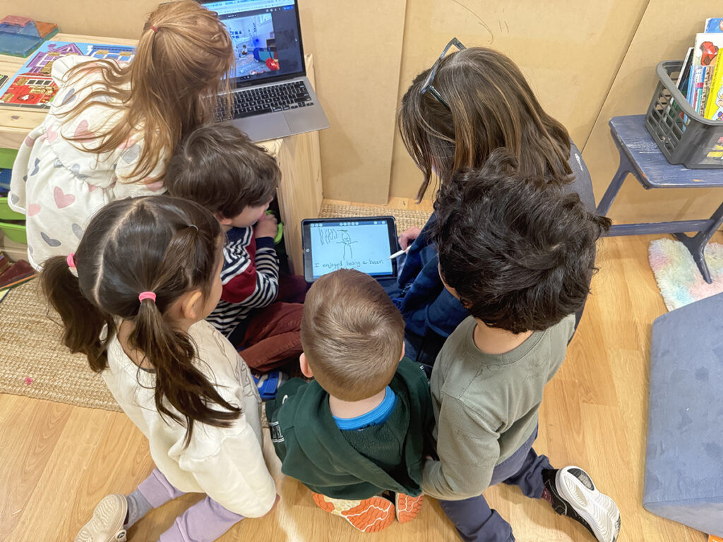group of elementary students working on a tablet an laptop
