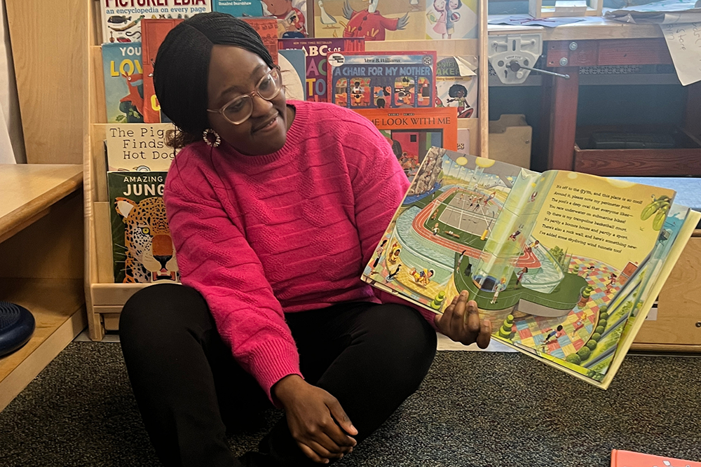 a teacher reading aloud a picturebook on the floor